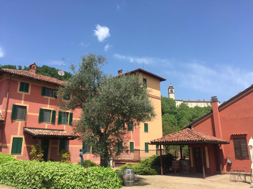 un groupe de bâtiments avec un arbre dans la cour dans l'établissement Tenuta Tenaglia, à Serralunga di Crea