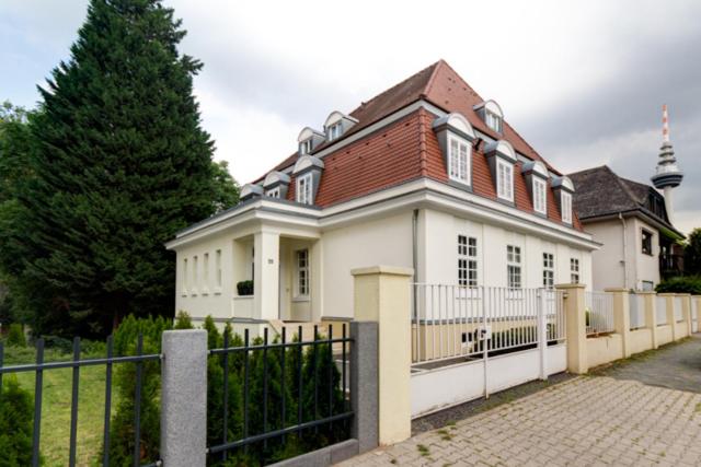 una casa blanca con una valla y un árbol en Die Villa en Mannheim