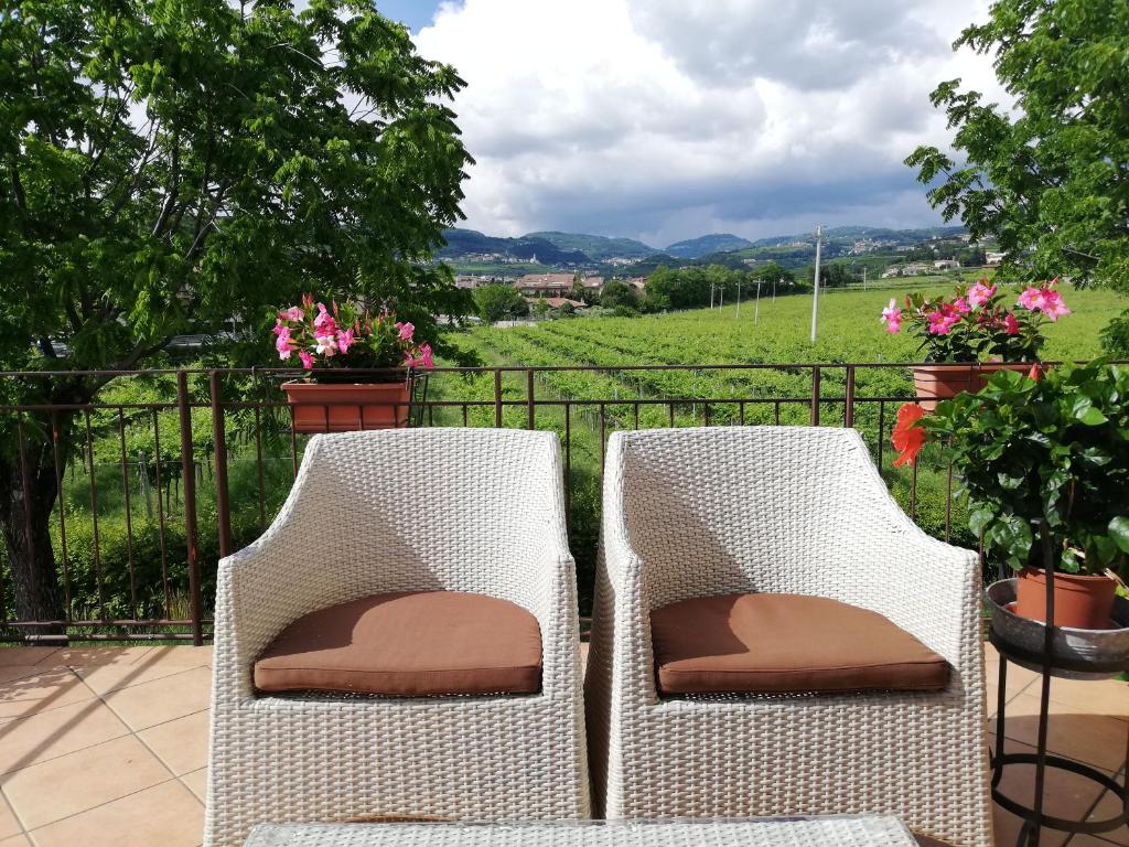 two white wicker chairs on a balcony with a view of a field at LA COQUILLE appartamento vicino all'ospedale in Negrar