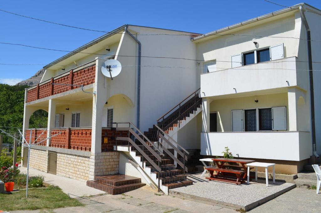 a white house with stairs and a table in front of it at Apartments Aneva in Baška