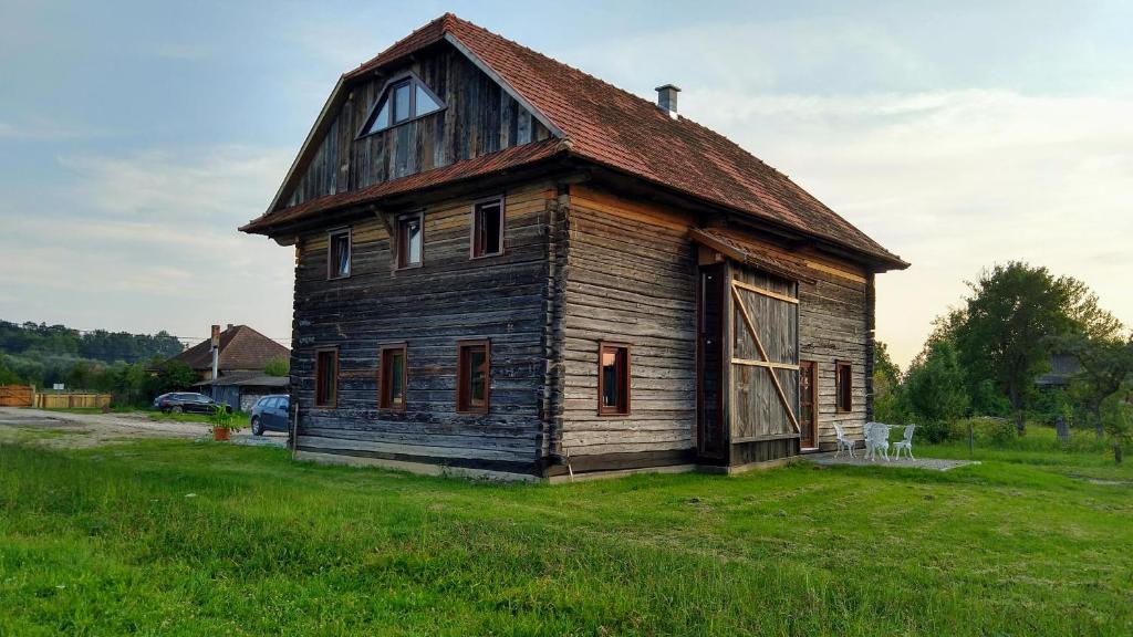 een oud huis in een grasveld bij Wooden Barn in Zăbala