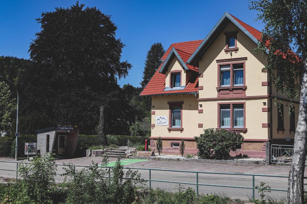 ein großes Haus mit rotem Dach in der Unterkunft Pension Heimat in Ottenhöfen