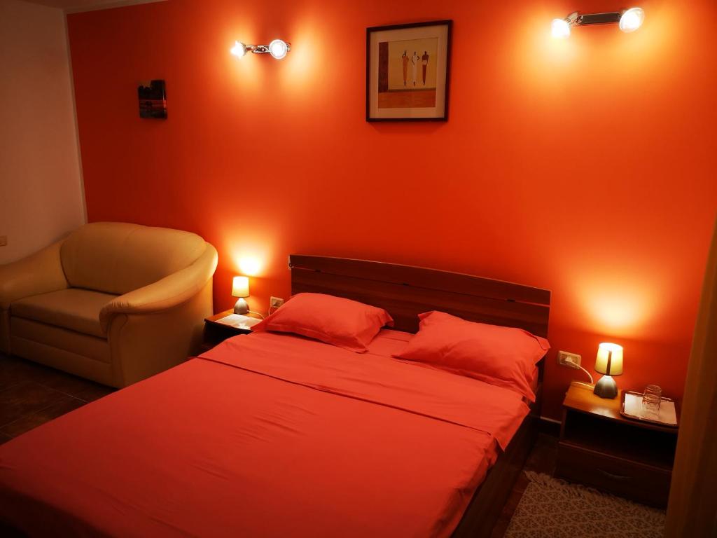 a bedroom with orange walls and a bed and a chair at Vila Sara in Chişoda