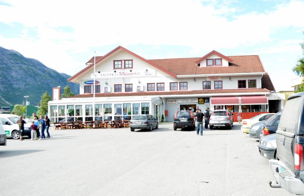 un grande edificio con auto parcheggiate in un parcheggio di HOTELLMILANO AS a Mosjøen