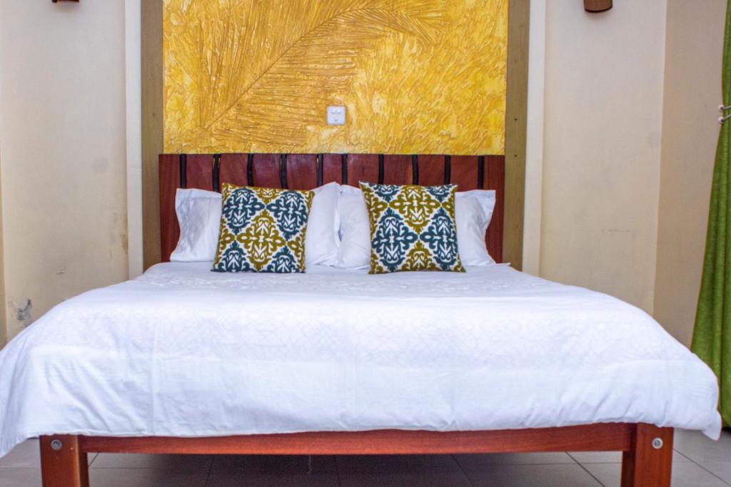 una cama con sábanas blancas y almohadas en Kasty L Studios and Apartments, en Nairobi