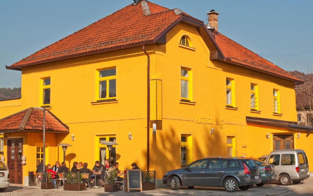 een geel gebouw met een groep mensen ervoor bij Hotel Katrca in Ljubljana