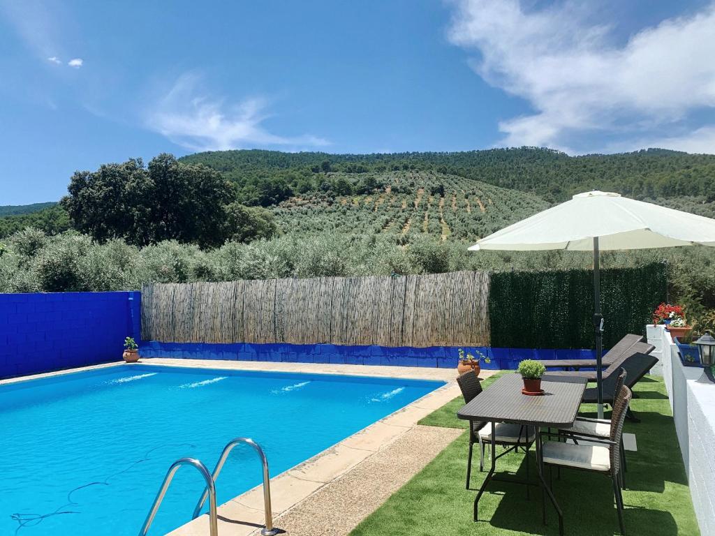 uma piscina com uma mesa e um guarda-sol em Cortijo El Pino em Cortijos Nuevos