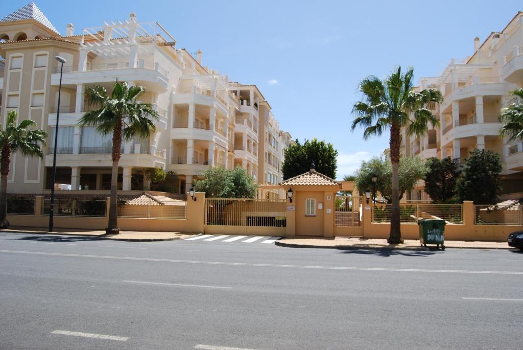 a street in front of a building with palm trees at Apartamentos Isla Canela y Punta del Moral in Isla Canela