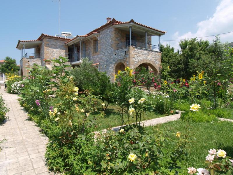 een huis met een tuin met bloemen ervoor bij angelastudios-stoupa in Stoupa