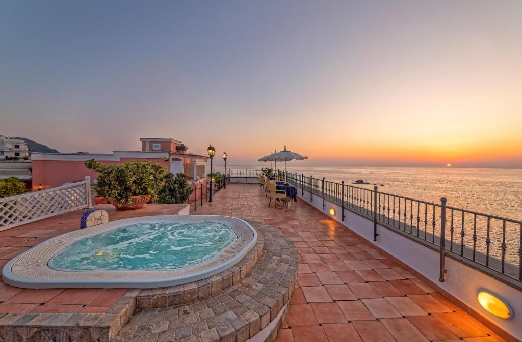 a hot tub on a patio next to the ocean at Hotel Nettuno in Ischia