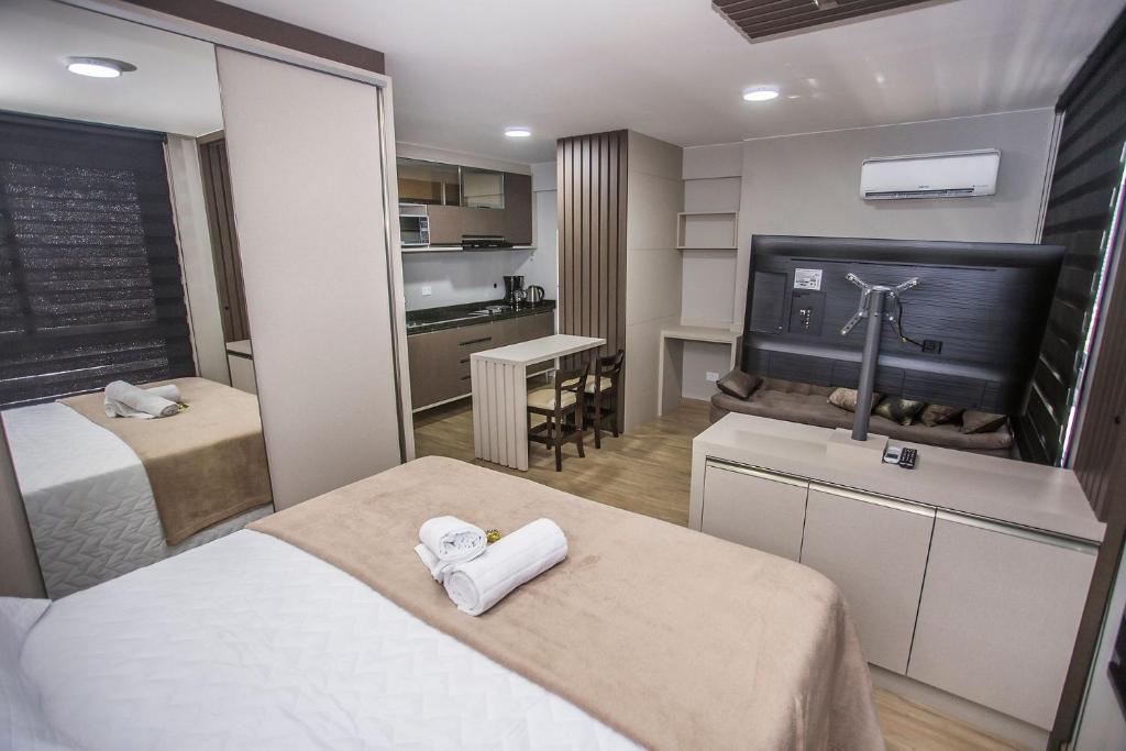 een hotelkamer met twee bedden en een keuken bij Studio com Cama e Sofá-Cama de Casal - ALL2011 in Curitiba