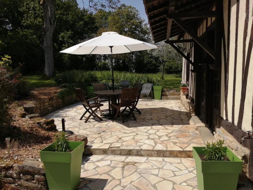 un patio con mesa y sombrilla en Domaine de l’épinerie Le fournil en Omméel