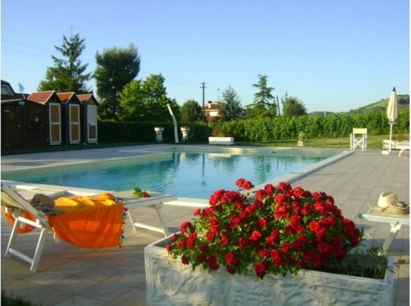 Montalto delle MarcheにあるCountry House Villa Geminianiの花が咲くスイミングプール(テーブル、椅子付)