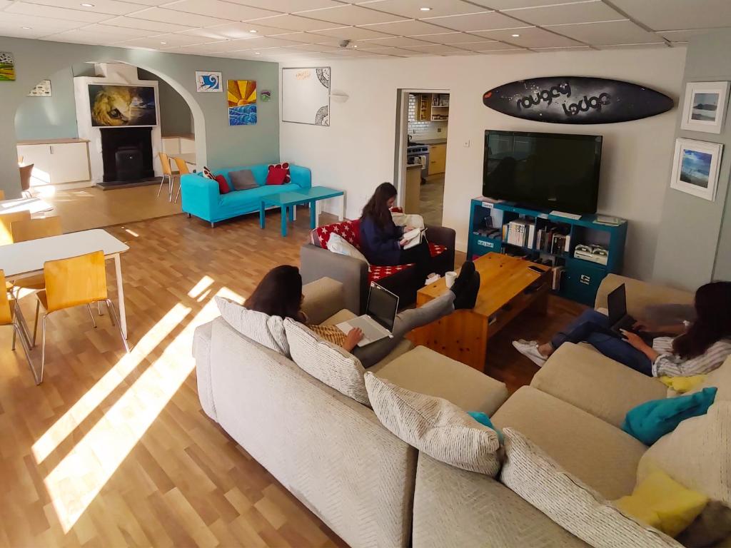 a group of people sitting on couches in a living room at Rougey Lodge Hostel in Bundoran