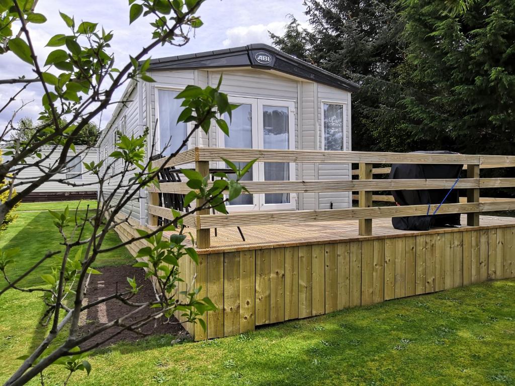 a tiny house with a wooden fence in a yard at Bynack Lodge in Boat of Garten