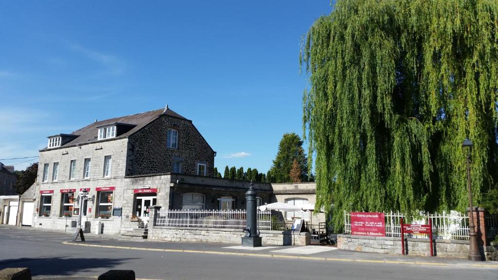 a building with a weeping willow tree next to a street at HOTEL L'AMERIVIERE*** in Aubrives