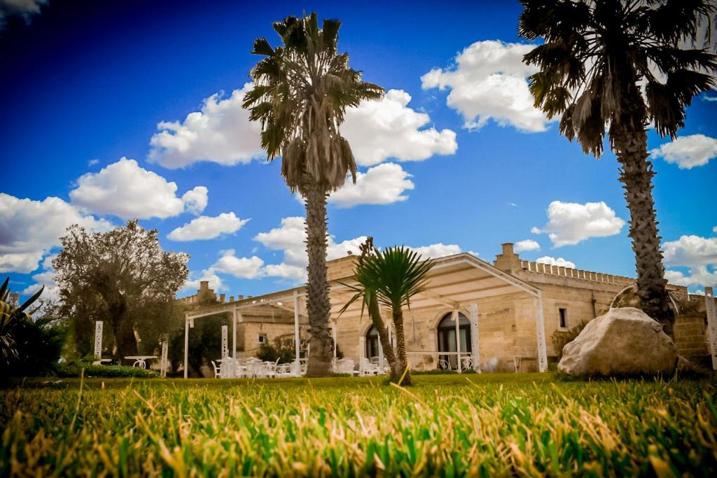 un edificio con palme di fronte ad esso di Masseria Tenuta Quintino a Torre Lapillo