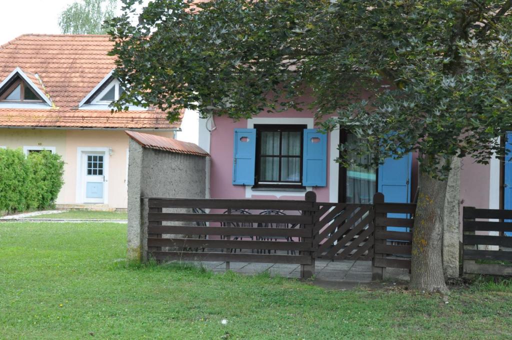una casa rosa y azul con una valla y un árbol en Apartma Julija Hiška 59, en Čatež ob Savi