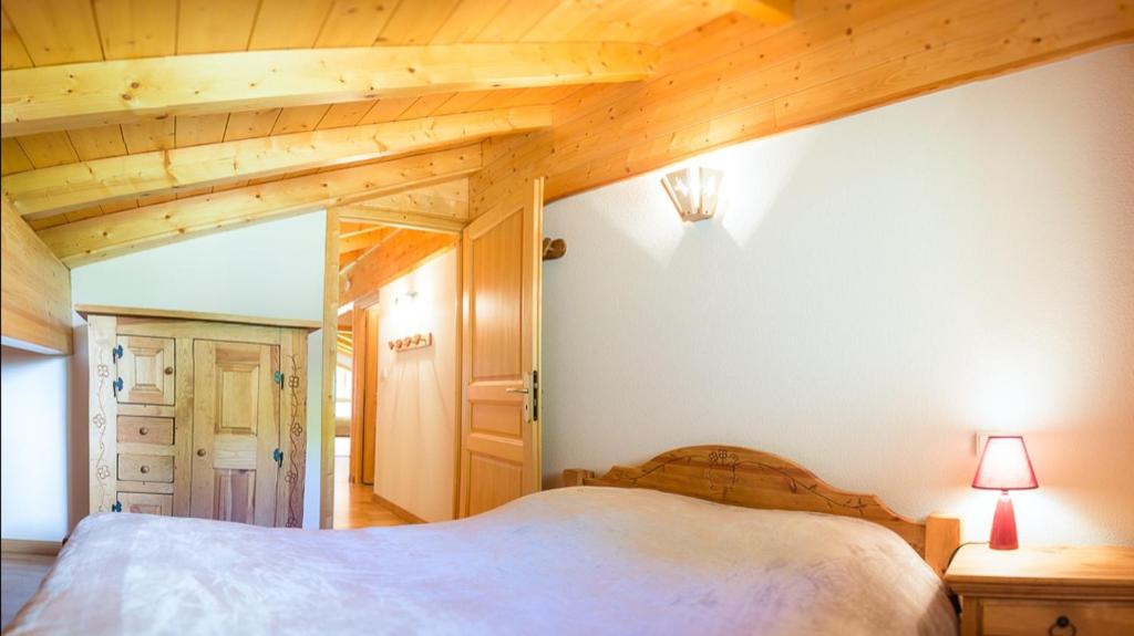 - une chambre avec un lit et un plafond en bois dans l'établissement Les Pins - Apt 11 - BO Immobilier, à Châtel