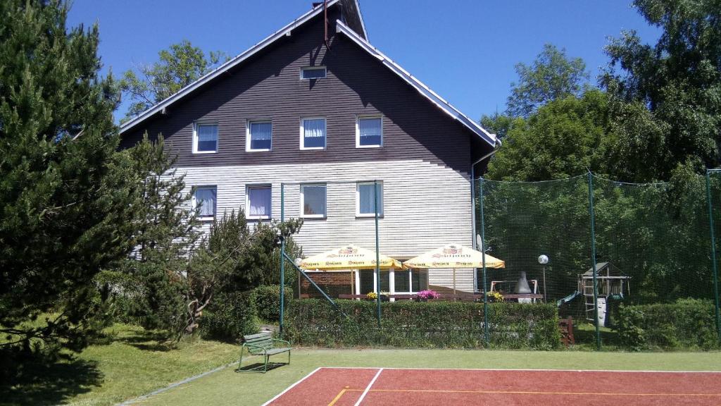 Penzion Kovářská في Kovářská: منزل كبير أمامه ملعب تنس