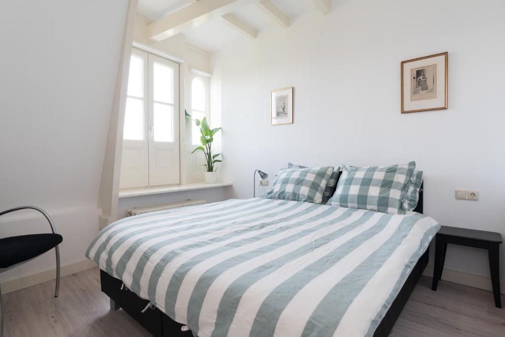 a white bedroom with a bed with a striped blanket at Central Rooftop Terrace Guest Suite in Amsterdam