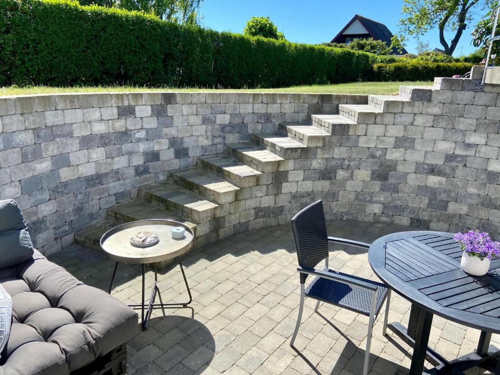 d'une terrasse avec une table, des chaises et un mur en briques. dans l'établissement Havgassens, à Sæby