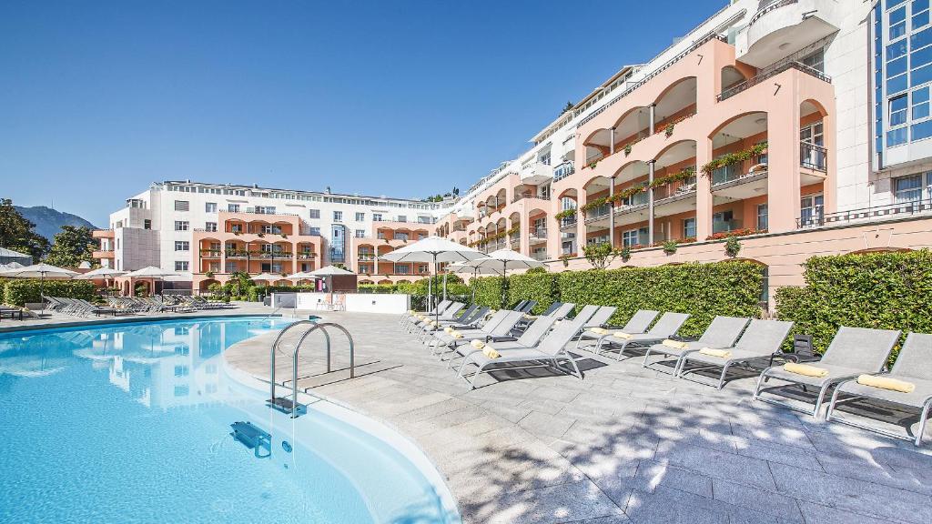 ルガノにあるVilla Sassa Hotel, Residence & Spa - Ticino Hotels Groupのラウンジチェア付きのスイミングプールが隣接しています。
