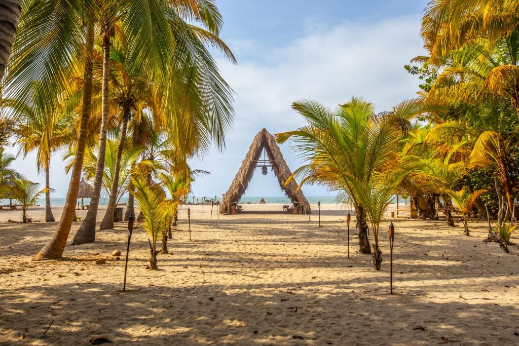 a wooden arch on a beach with palm trees at Gitana del Mar Boutique Beach Resort in Buritaca