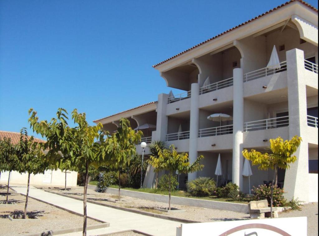 un grand immeuble d'appartements avec des arbres devant lui dans l'établissement APPARTEMENT DUPLEX PORTICCIO Centre, à Porticcio
