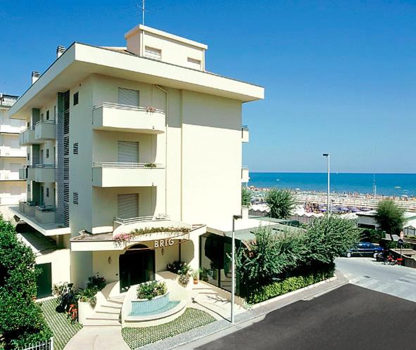 een groot wit gebouw met de oceaan op de achtergrond bij Hotel Brig in Riccione
