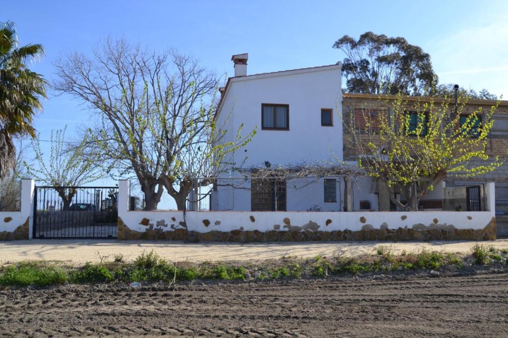 une maison blanche avec une clôture et des arbres dans l'établissement Masia Tarranc, à Els Muntells