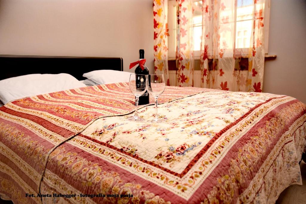 un letto con una trapunta e due bicchieri di vino sopra di Amber Apartments a Danzica