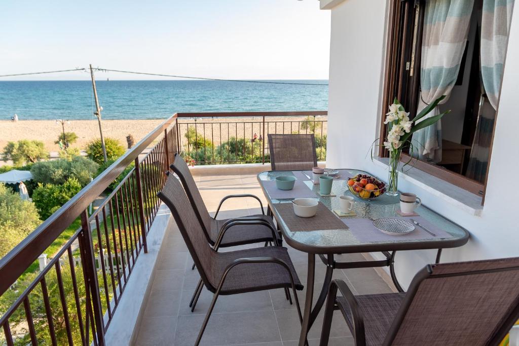 a table on a balcony with a view of the beach at Dimi Seafront Apartment by Rentals Pro - Nea Moudania in Nea Moudania