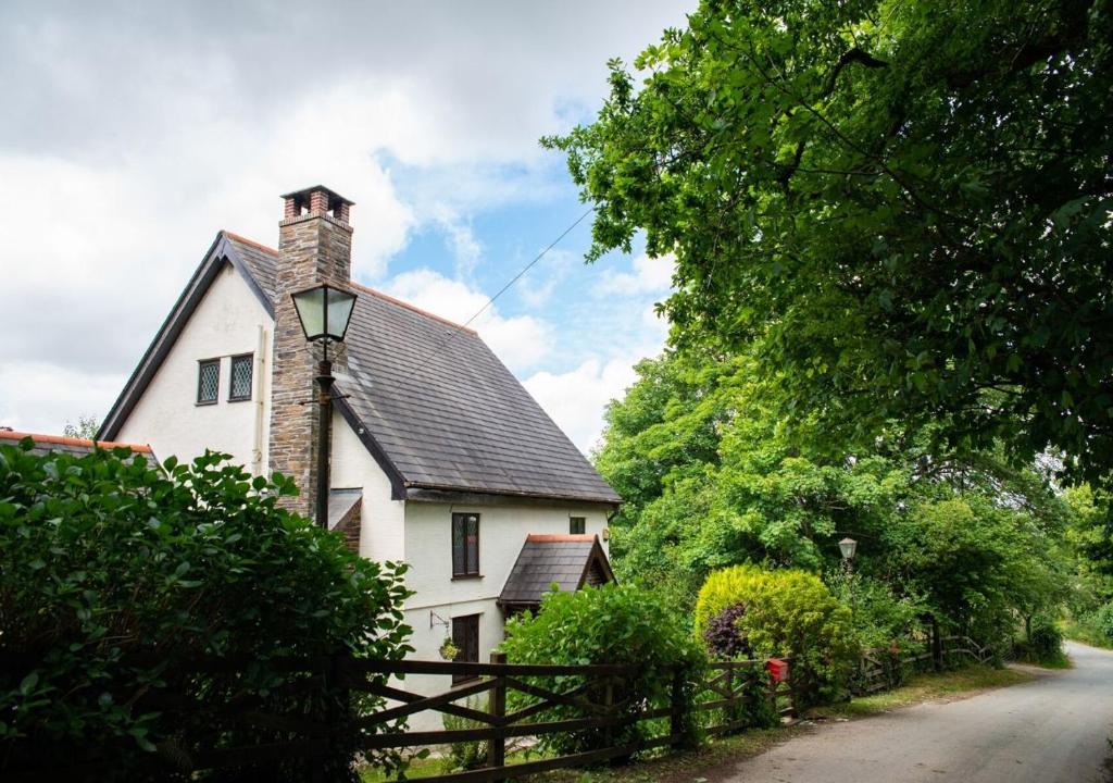 a white house with a chimney and a fence at Demelza Cottage Apartment in Bodmin