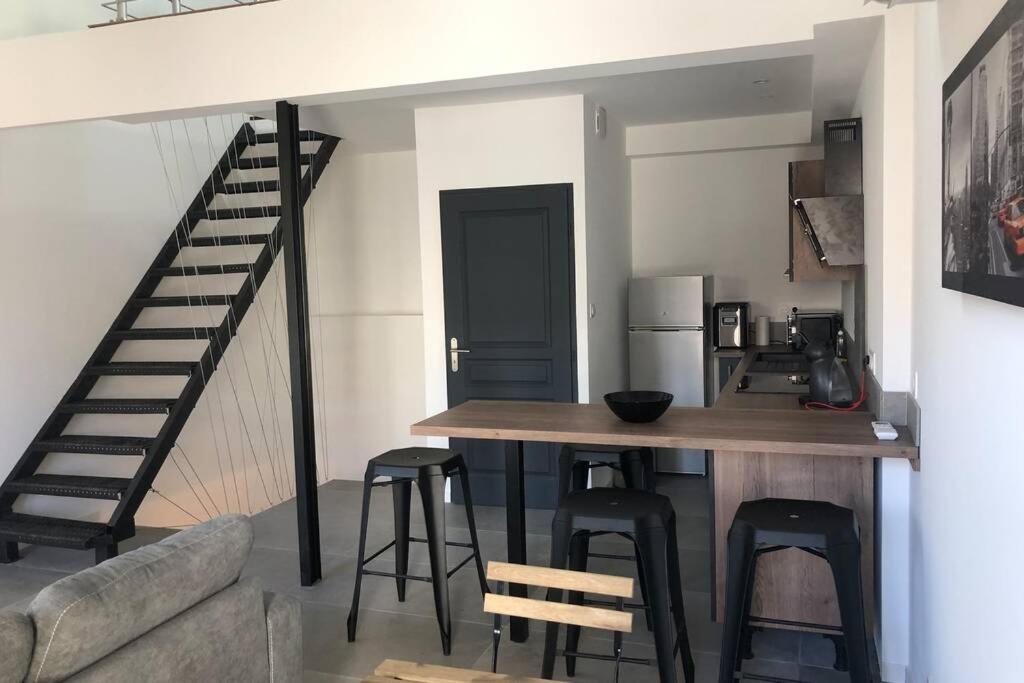 uma cozinha com um bar com bancos e uma escadaria em Charmante maison à 5min de Marcoule em Codolet