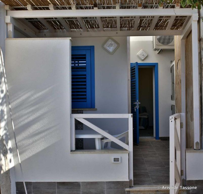 een wit huis met een blauwe deur en een veranda bij Il Cortiletto su levanzo in Favignana