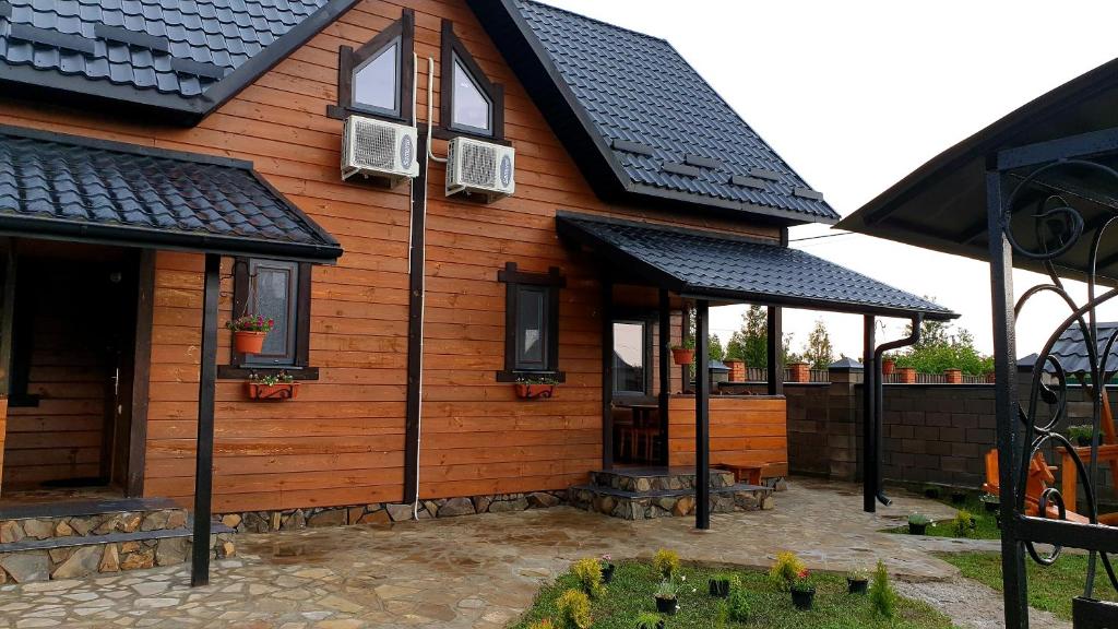 a wooden house with black roofs and a patio at Садиба For Rest in Svityazʼ