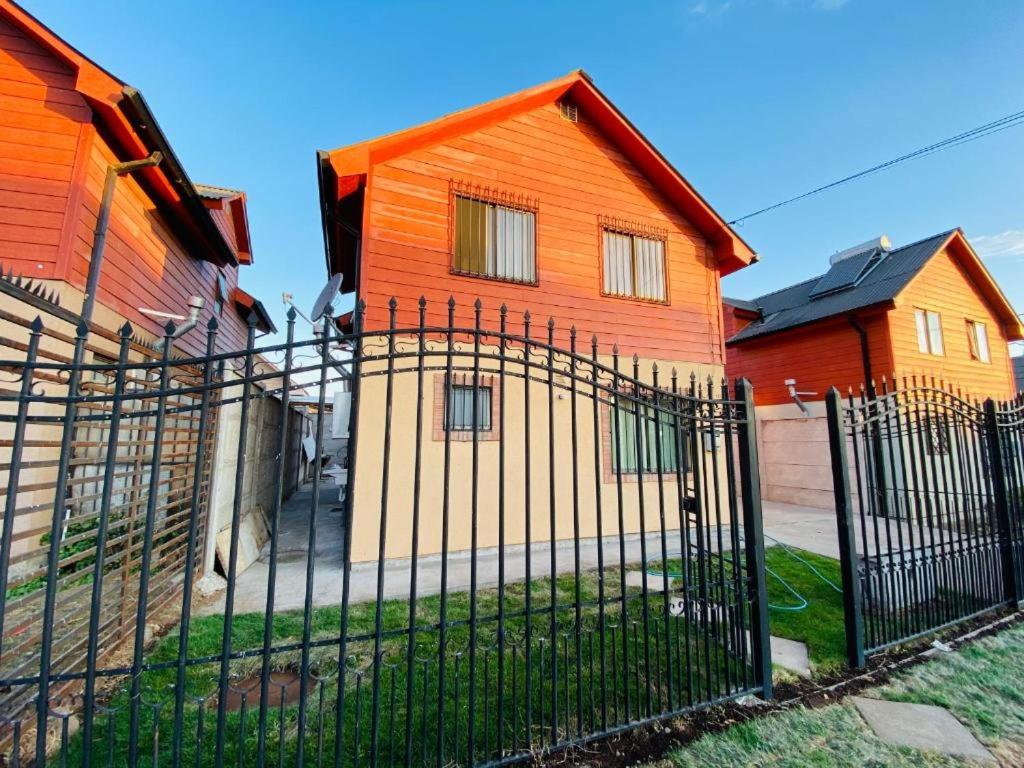 uma casa laranja com uma cerca em frente em Cabañas Del Maule II em Talca