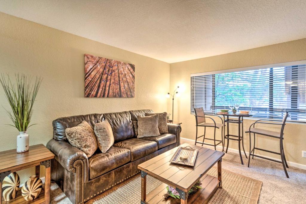 a living room with a leather couch and a table at Sunny Sedona Condo with Resort Pool and Grill Access! in Sedona