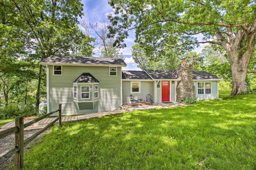 a green house with a red door in a yard at Our Lakeside Retreat with Deck on Lake Herrington! in Bushtown