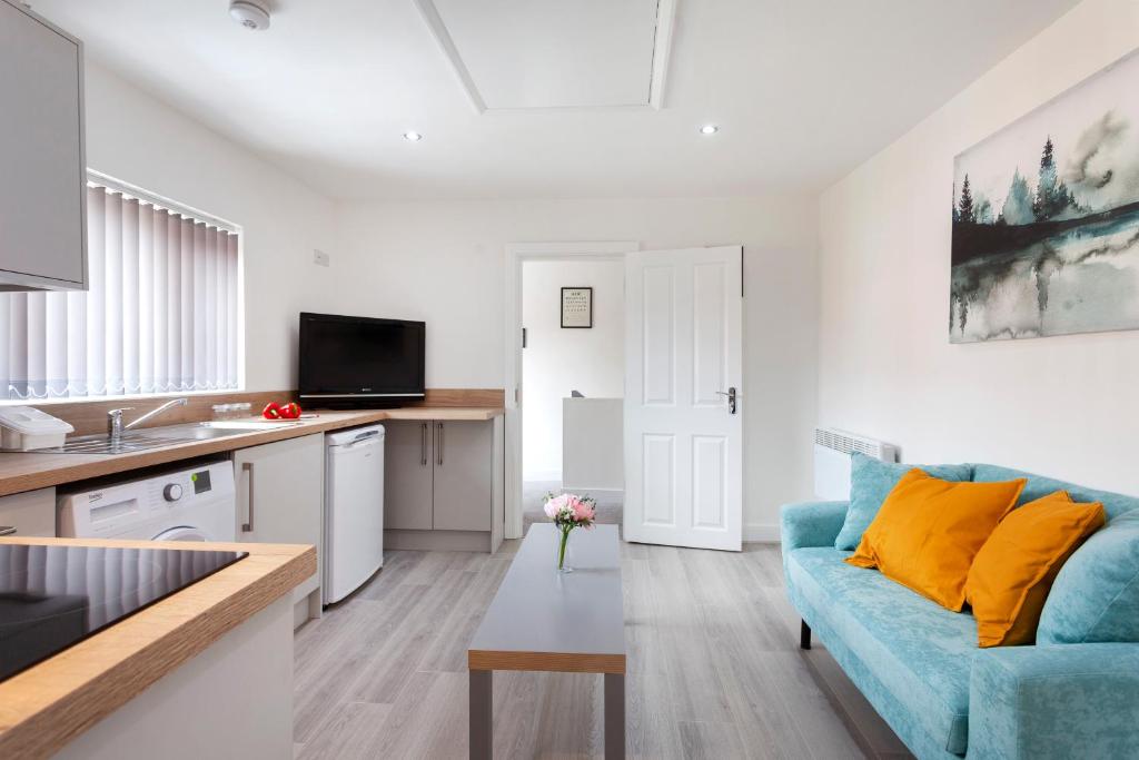 ein Wohnzimmer mit einem blauen Sofa und einer Küche in der Unterkunft Smart Apartment Close2City in Leicester