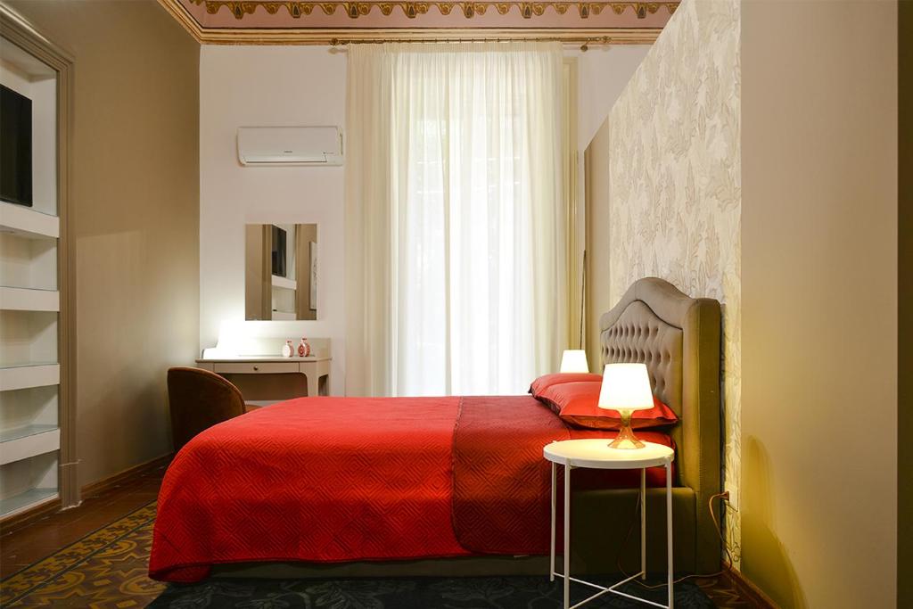 sypialnia z czerwonym łóżkiem i oknem w obiekcie Filomena Suite Luxury Apartment w Katanii