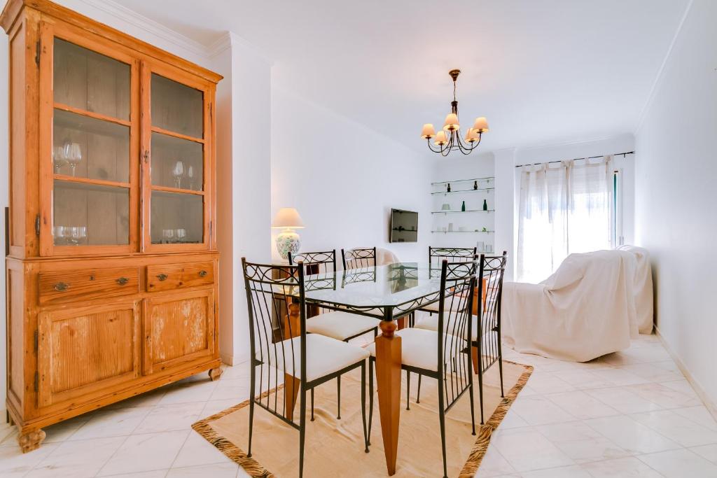 uma sala de jantar com uma mesa de vidro e cadeiras em Mango Apartment - Faro city center em Faro