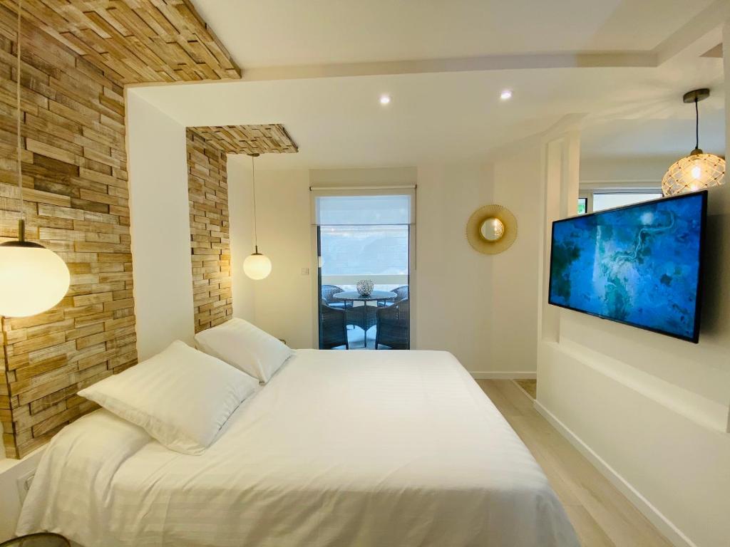 a bedroom with a white bed and a flat screen tv at Feel@Home Nemausus « Le 11 » in Nîmes