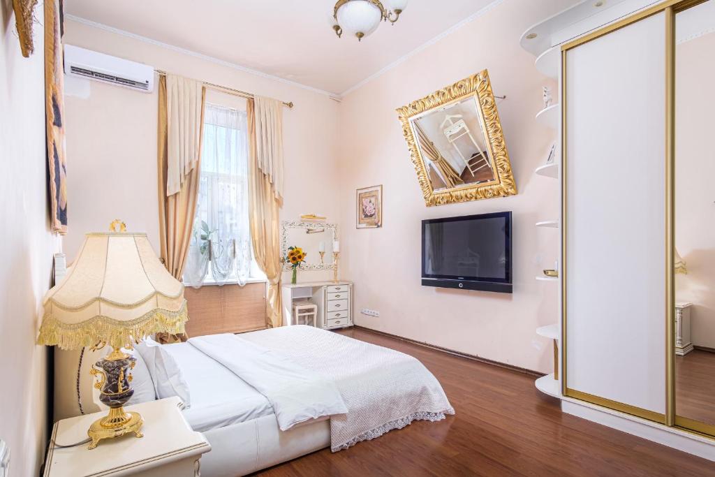 a white bedroom with a bed and a tv at Ekaterina Apartments - Odessa in Odesa