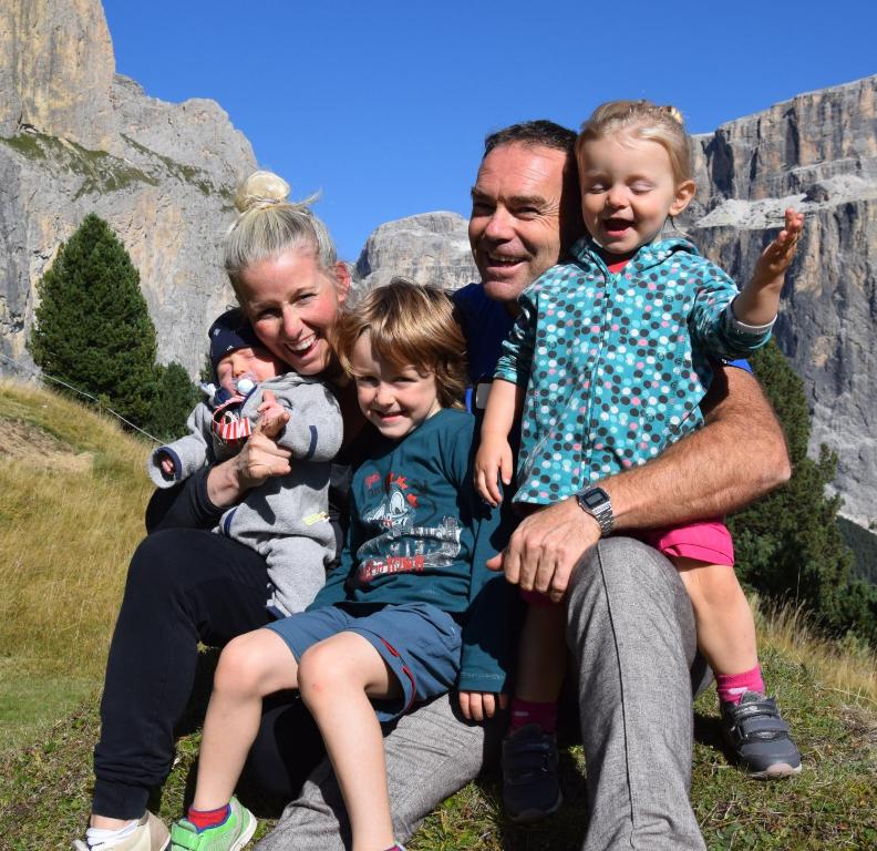 a family posing for a picture in front of a mountain at Garni Ortles in Selva di Val Gardena