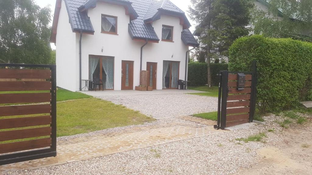 a white house with a blue roof and a gate at DOMKI "apartamenty 4maki" in Jastrzębia Góra