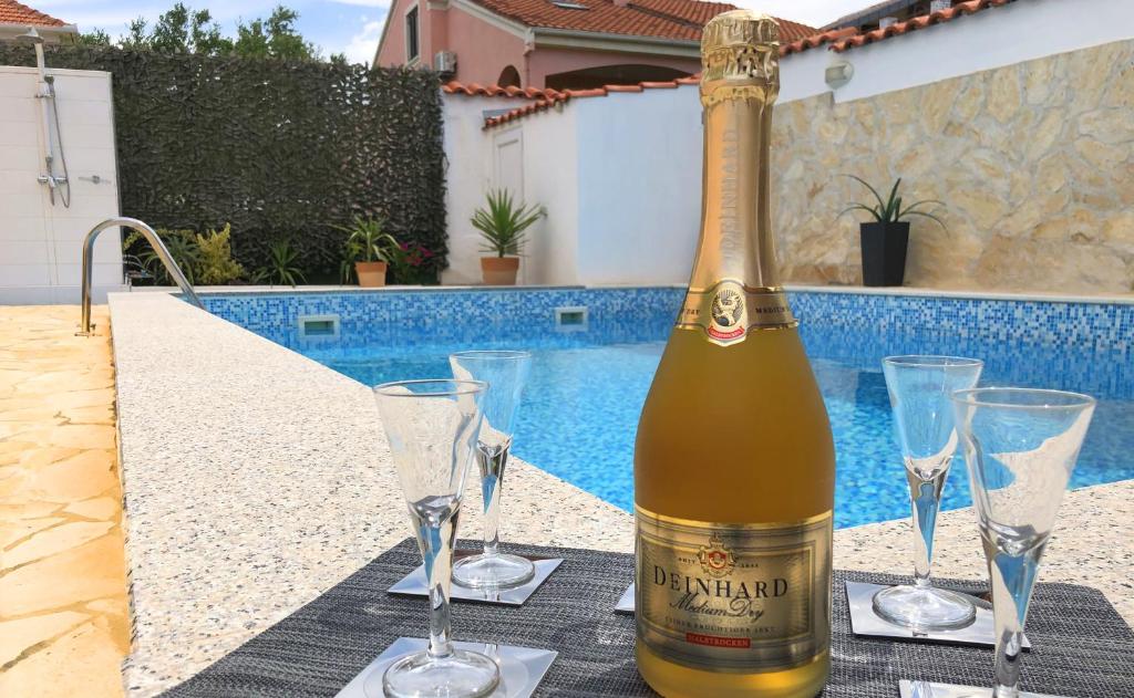Villa Sanda with Private Pool في زادار: زجاجة من النبيذ موضوعة على طاولة مع كؤوس للنبيذ