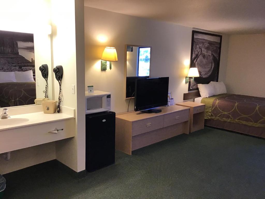a hotel room with a bedroom with a bed and a television at Arch Canyon Inn in Blanding