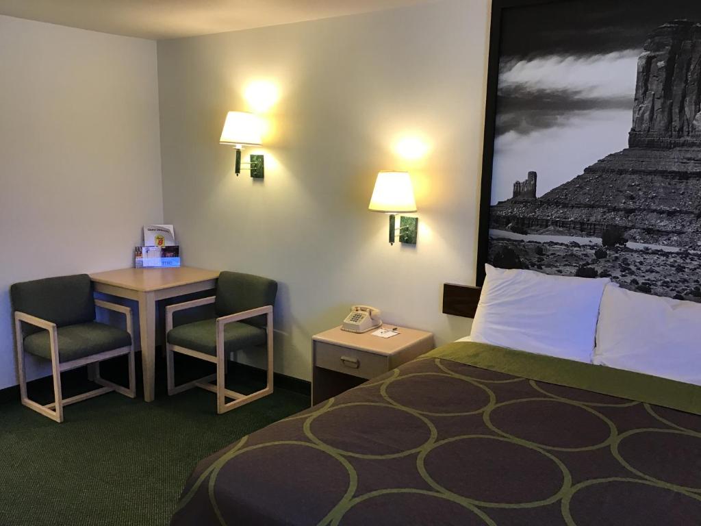 a hotel room with a bed and a desk with a phone at Arch Canyon Inn in Blanding
